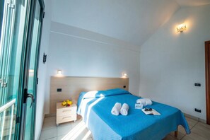 Ein Hotelzimmer mit Bett, Nachttisch, kleinem Tisch mit Lampe und Tür.