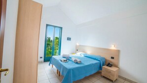 Un dormitorio con cama, mesita de noche y puerta que da a un balcón.