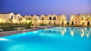 Un hotel con piscina, varias edificaciones con ventanales arqueados y zonas de estar al aire libre.