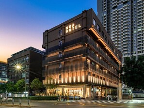 Un hotel de varios pisos con fachada moderna, señalización iluminada y entrada a nivel de calle.