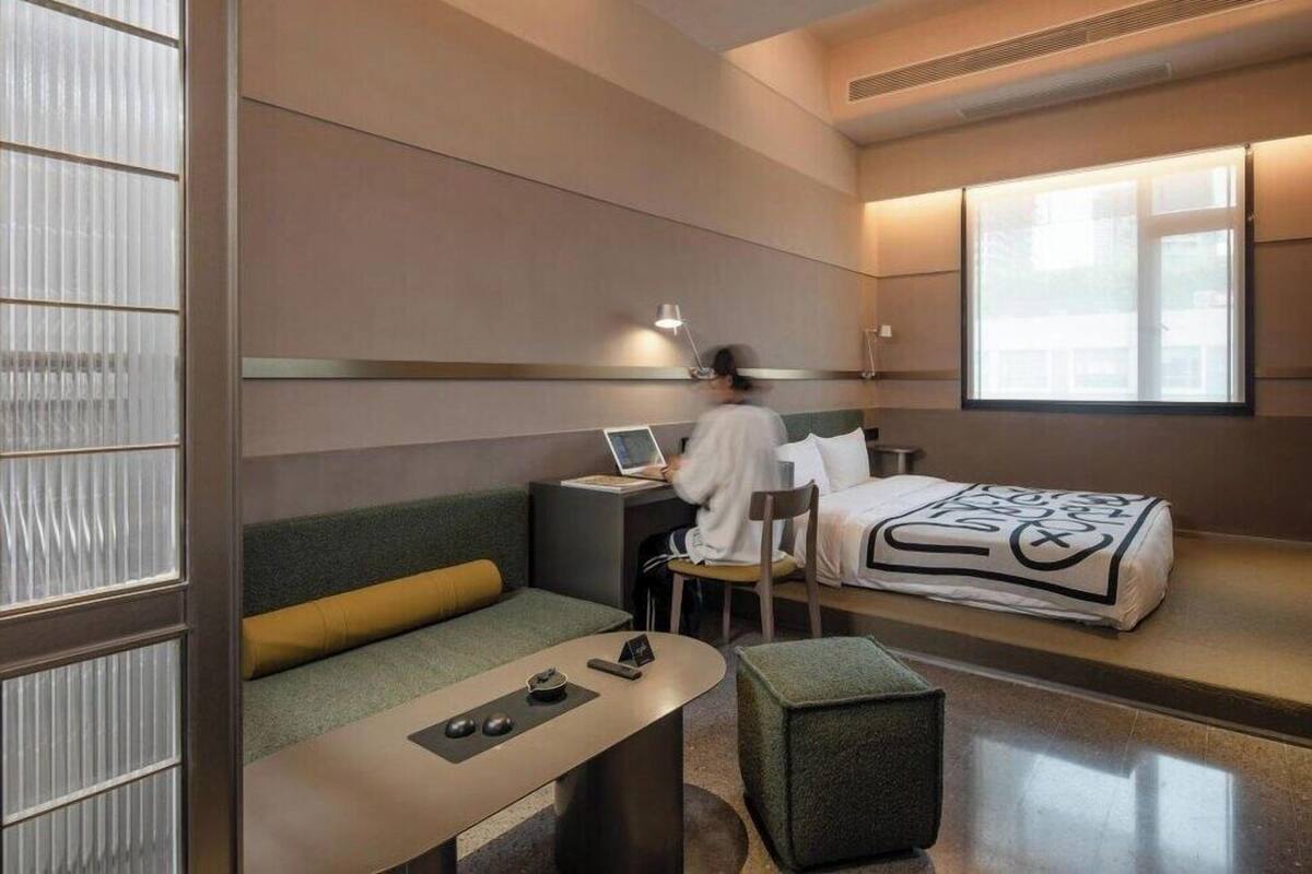 Quarto de hotel moderno com uma cama, uma mesa de escritório, uma cadeira, um sofá e uma pequena mesa.