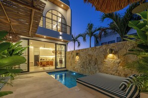 A modern house with a swimming pool, a dining area, and a stone wall. - Mareo Villa (Pecatu)