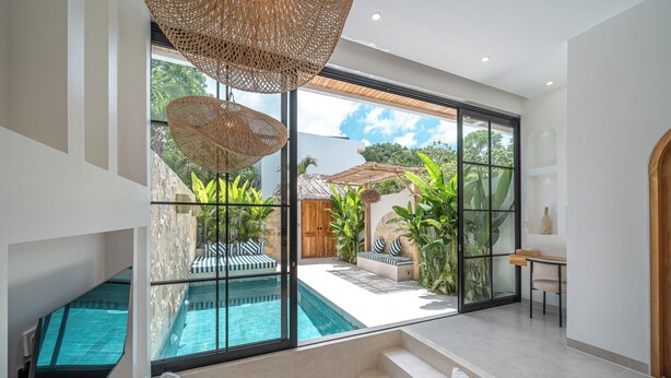 Et moderne interiør med en pool, store vinduer og en trappe op til en balkon.