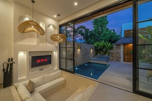 Ein modernes Wohnzimmer mit Flachbildfernseher, Pool und Steinwand.