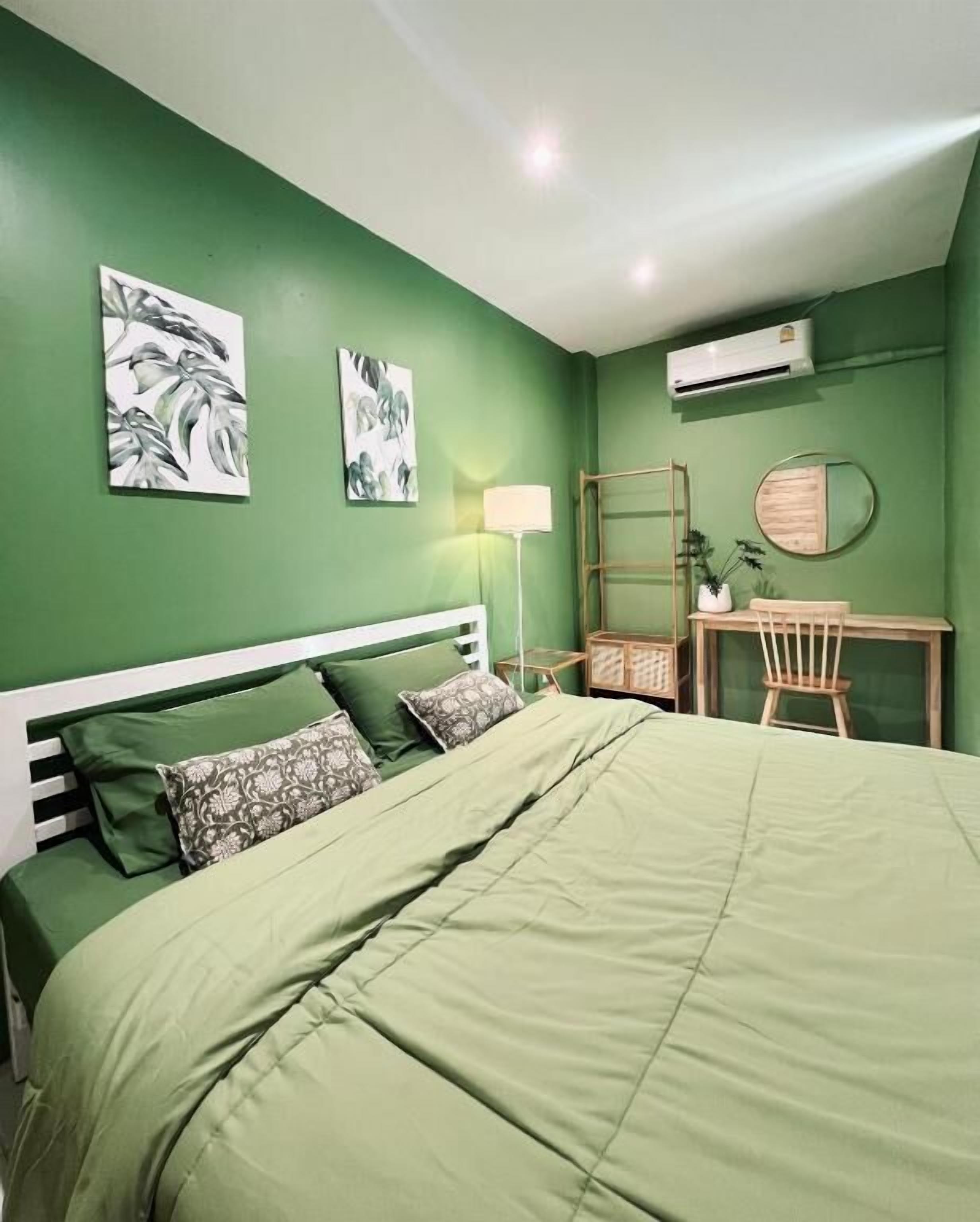 A room with a bed, a desk, a chair, a mirror, and wall art.
