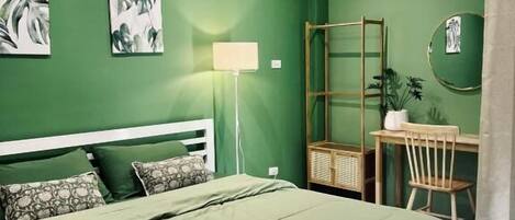 Un dormitorio con cama, escritorio, silla, aire acondicionado y obras de arte en las paredes.