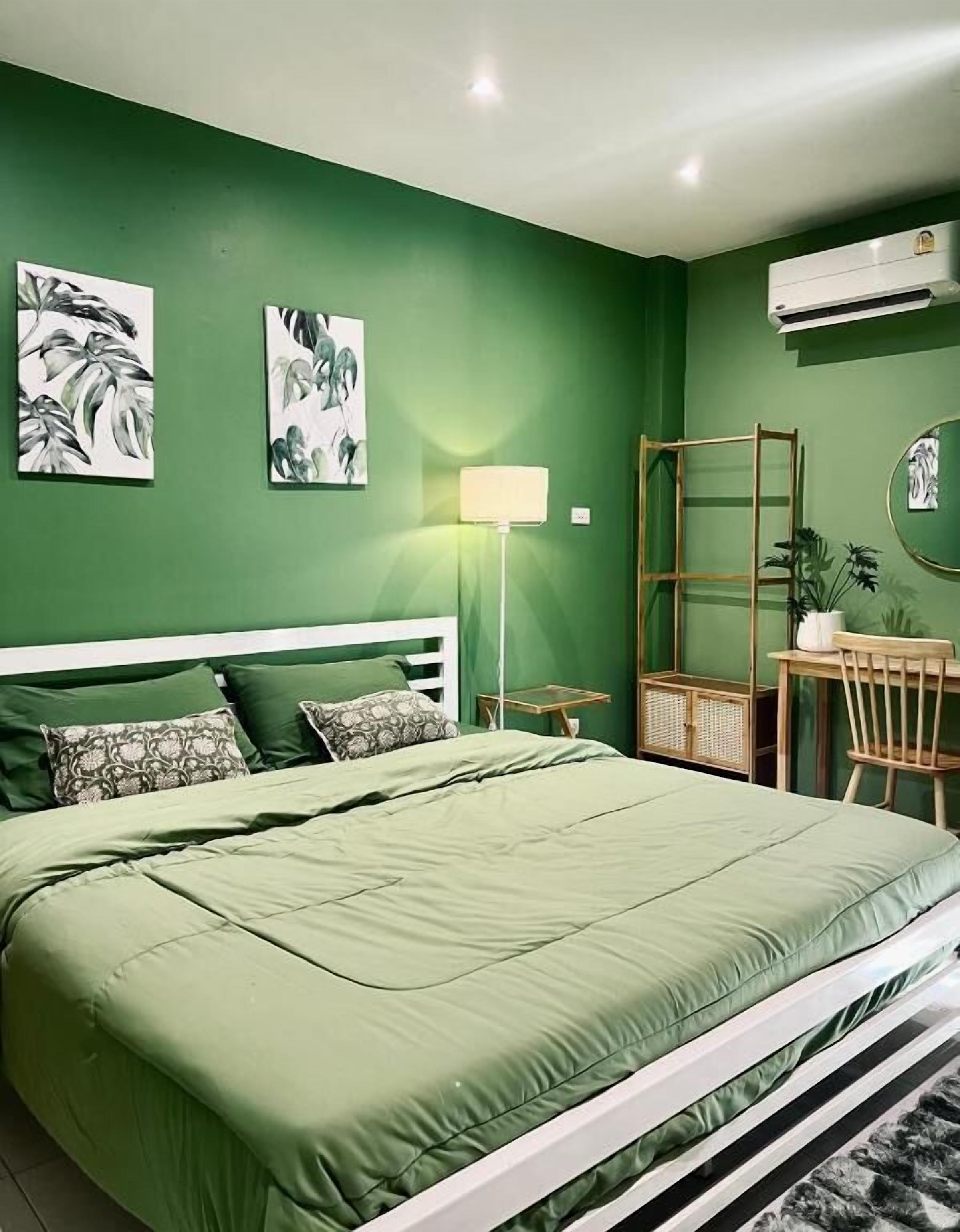Una habitación con cama, escritorio, silla, lámpara y decoración en la pared.