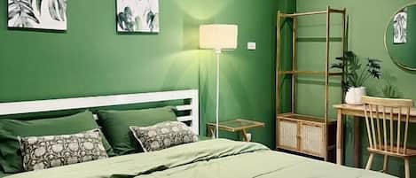 A room with a bed, a desk, a chair, a lamp, and wall art.