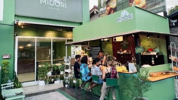 A two-story building with a green facade, a sign reading 'MIDORI,' and a small outdoor seating area with tables and chairs. - Midori Rawai (Rawai)