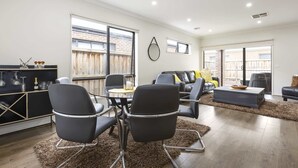 Un grand espace de vie comprenant une table à manger, des chaises, un canapé et un téléviseur.