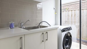 Une cuisine équipée d’un évier, d’un lave-linge et d’une fenêtre.