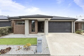 A modern two-story house with a garage, a well-maintained lawn, and a small garden area.