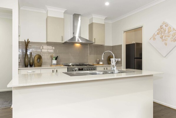 A modern kitchen with a central island, stainless steel appliances, and a decorative wall piece.