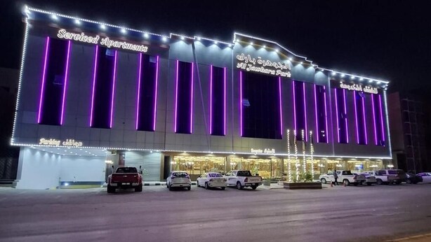 A building with 'Serviced Apartments' signage, a parking area, and a 'Parked Cars' sign. - Al Jawhara Park (Riyadh)