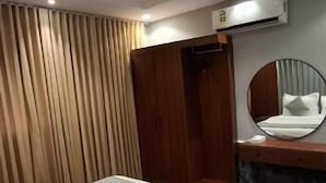 A hotel room with two beds, a wooden wardrobe, a round mirror, and an air conditioning unit. - Al Jawhara Park (Riyadh)