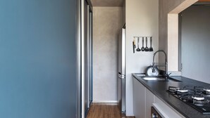 Een moderne keuken met houten vloeren, een zwart aanrecht en een roestvrijstalen spoelbak.