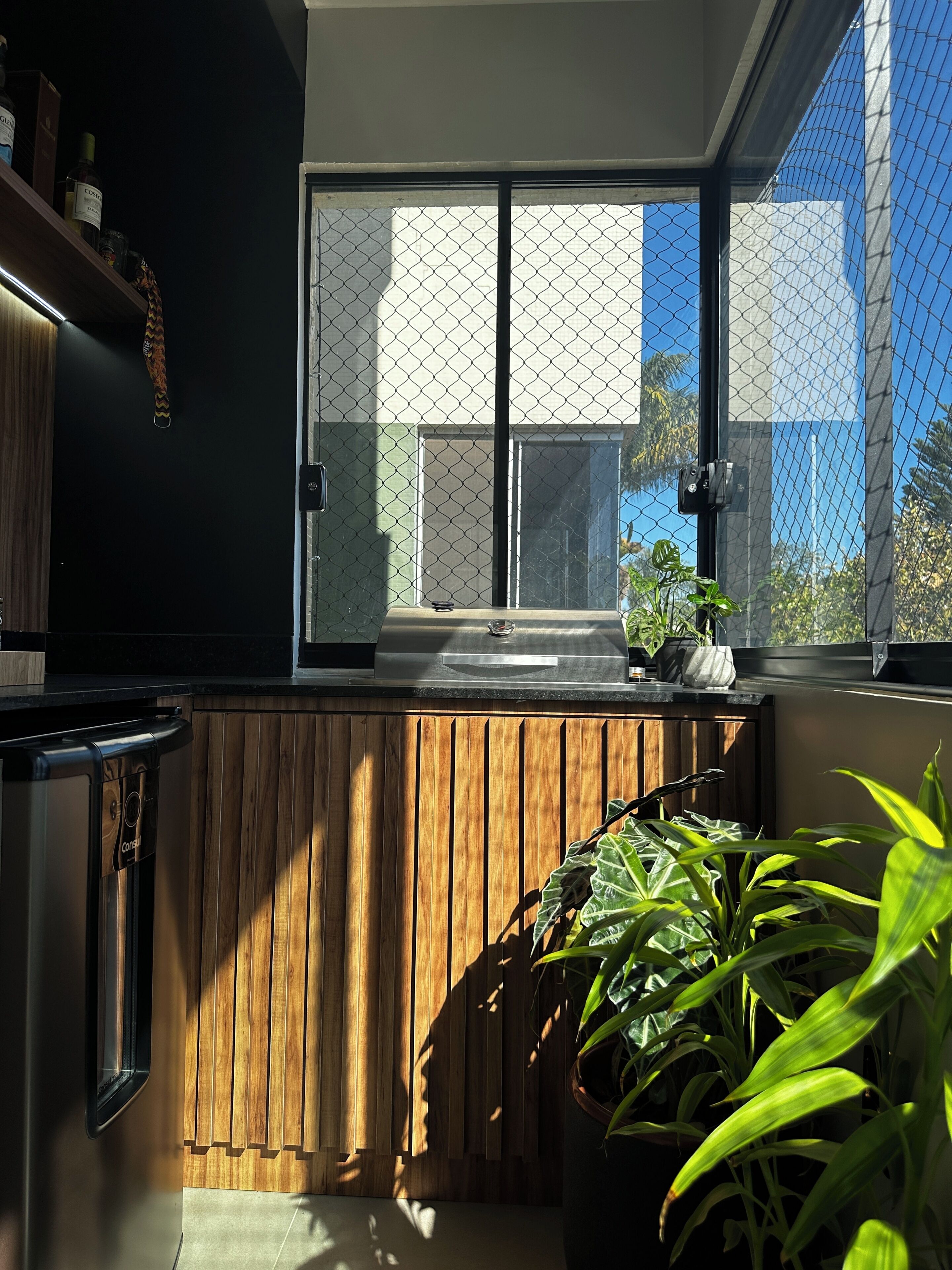 A modern kitchen with a wooden countertop, a built-in dishwasher, and a large window with a view of the outside.