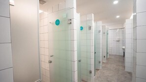 Een rij glazen toiletten met witte betegelde wanden en een betegelde vloer.