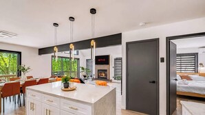 A modern kitchen with a central island, a dining area with orange chairs, and a living space with a fireplace. - Lakefront Modern Escape with Hot Tub (East Stroudsburg)