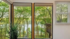 Una stanza con un'ampia finestra vista su un lago e alberi.