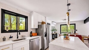 A modern kitchen with white cabinets, stainless steel appliances, and a large island. - Lakefront Modern Escape with Hot Tub (East Stroudsburg)
