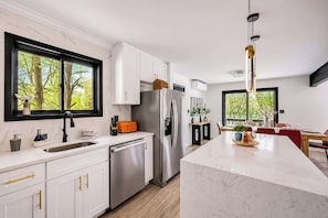 Cozinha moderna com armários brancos, eletrodomésticos de aço inoxidável e uma ilha grande.