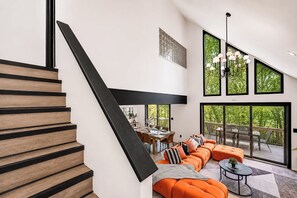 Un interno moderno con una scala, un'area da pranzo e una zona relax con ampie finestre.