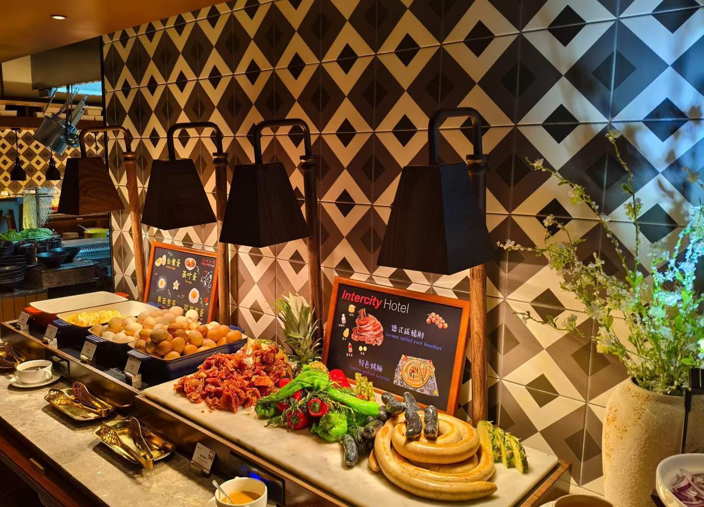 A buffet with various dishes, including dumplings, grilled meat, and vegetables, with a sign indicating the hotel name.