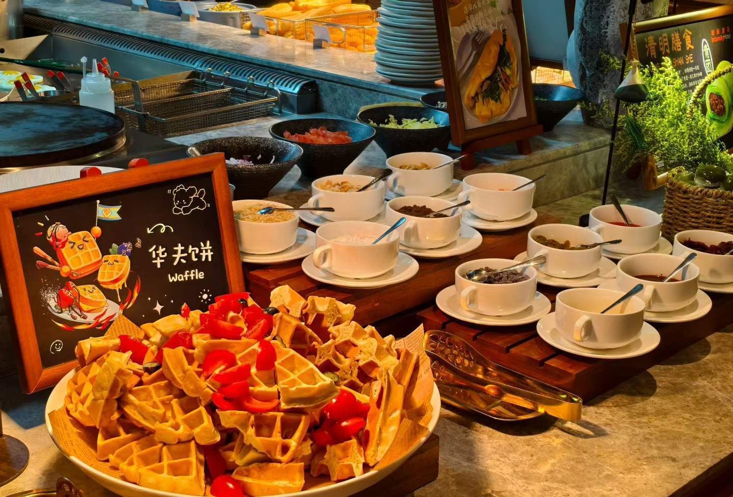 Buffet com waffles, sopas em tigelas e placa de waffles.