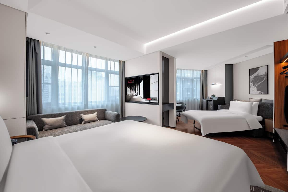 Una habitación de hotel con dos camas, un sofá, un escritorio y un televisor.