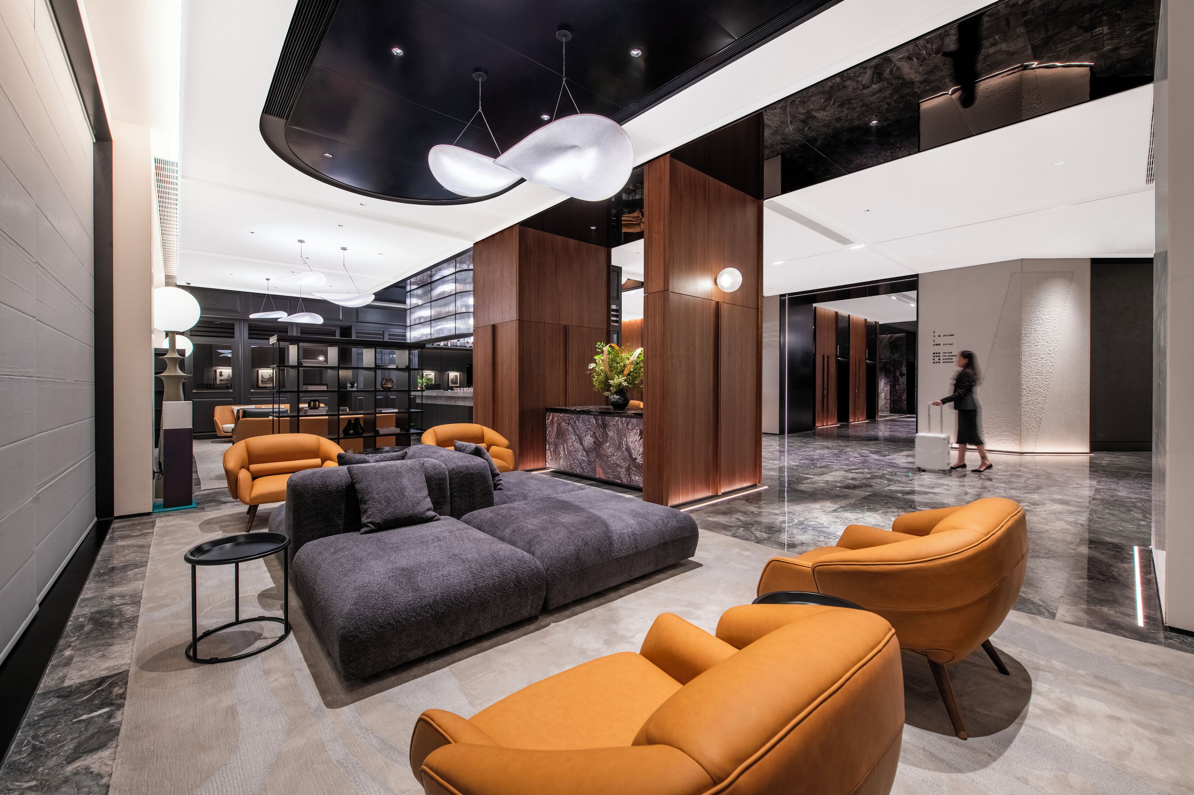 A modern lobby with a sectional sofa, armchairs, a small table, and a potted plant.