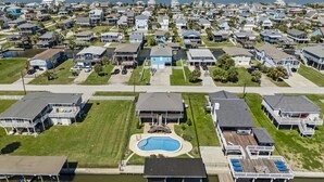 A residential area with houses, a swimming pool, and a waterfront view. - Relaxed Beach Getaway with Canal Views (Galveston)