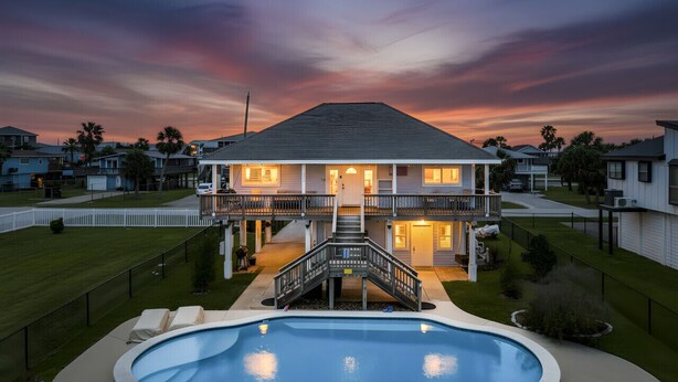 A two-story house with a swimming pool, a covered patio, and a well-maintained lawn. - Relaxed Beach Getaway with Canal Views (Galveston)