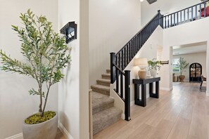 A staircase with a black railing, a potted plant, and a light-colored wall. - Family-Friendly 4BR Home, 30+ Night Stays -  Loft, Big Backyard (Gilbert)