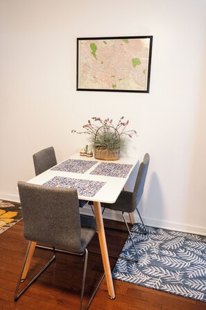 Un coin repas comprenant une table, des chaises, une carte accrochée au mur, une plante et un tapis à motifs.