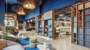 Un hall d’entrée moderne avec des espaces de détente, un comptoir d’accueil et une bibliothèque.