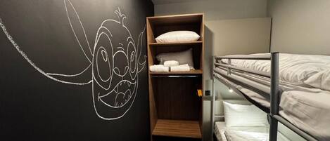 Habitación con literas, un armario de madera y un mural en la pared.