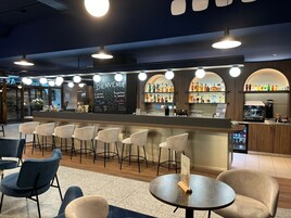 A bar area with a counter, bar stools, and a seating area with tables and chairs.