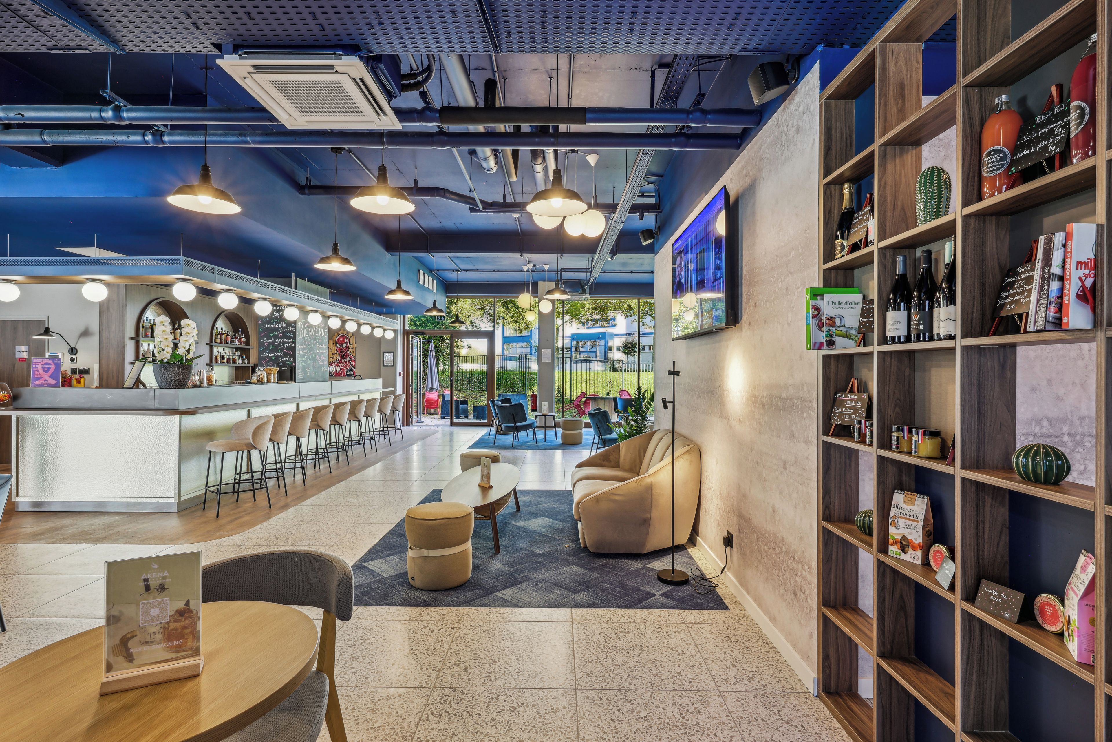 Un bar moderno con mostrador, asientos y una estantería con diversos objetos.