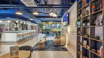 Un bar moderno con mostrador, asientos y una estantería con diversos objetos.