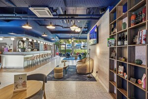 Un bar moderno con mostrador, asientos y una estantería con diversos objetos.