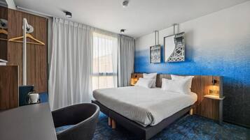 Ett modernt hotellrum med en stor säng, ett skrivbord, en stol och en garderob.