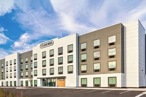 Een meerlaags hotel met een moderne gevel, veel ramen en een heldere lucht.