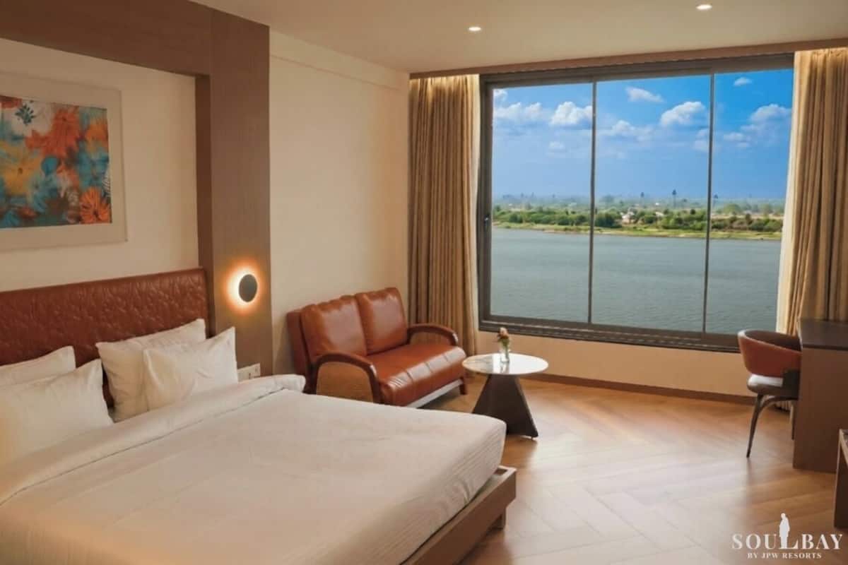 Habitación de hotel con cama, sofá, una mesita y vista a un cuerpo de agua.