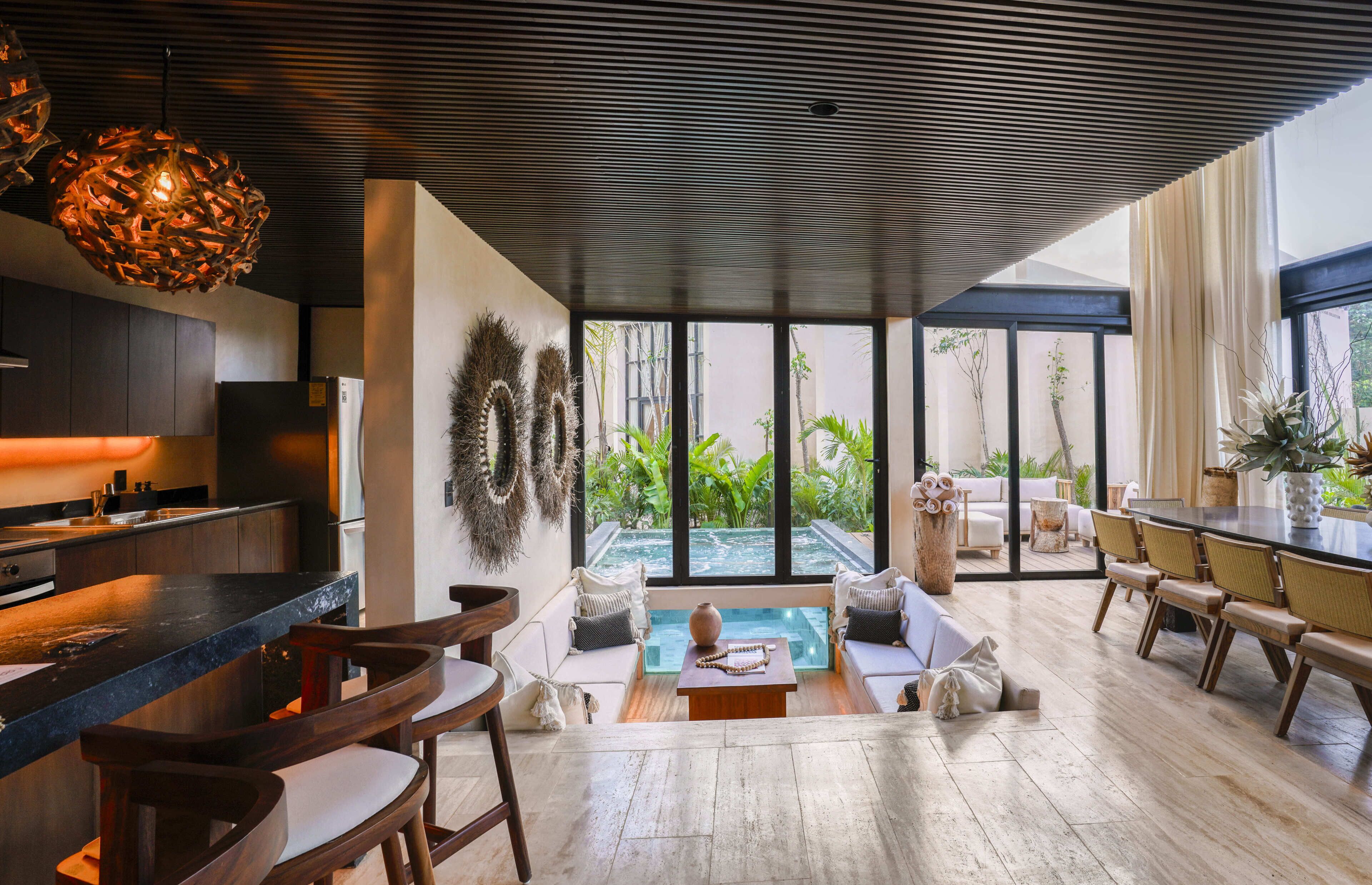 A modern kitchen with a bar area, a seating area with a view of a pool, and a dining area with a large table and chairs.