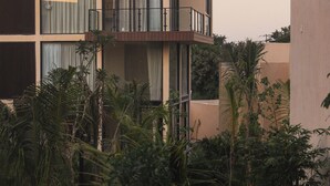 A multi-story building with balconies, surrounded by dense tropical vegetation. - Trobbu (Tulum)