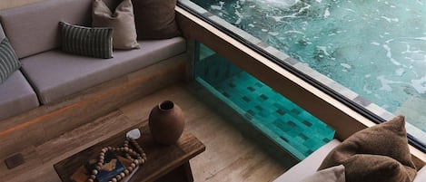 A spa area with a hot tub, a wooden bench with a vase and book, and a sofa with cushions.