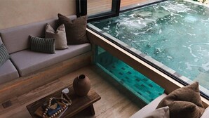 A spa area with a hot tub, a wooden bench with a vase and book, and a sofa with cushions. - Trobbu (Tulum)
