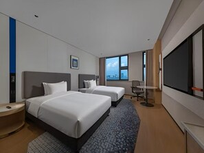 Habitación de hotel con dos camas, un ventanal grande, un televisor de pantalla plana y un escritorio.