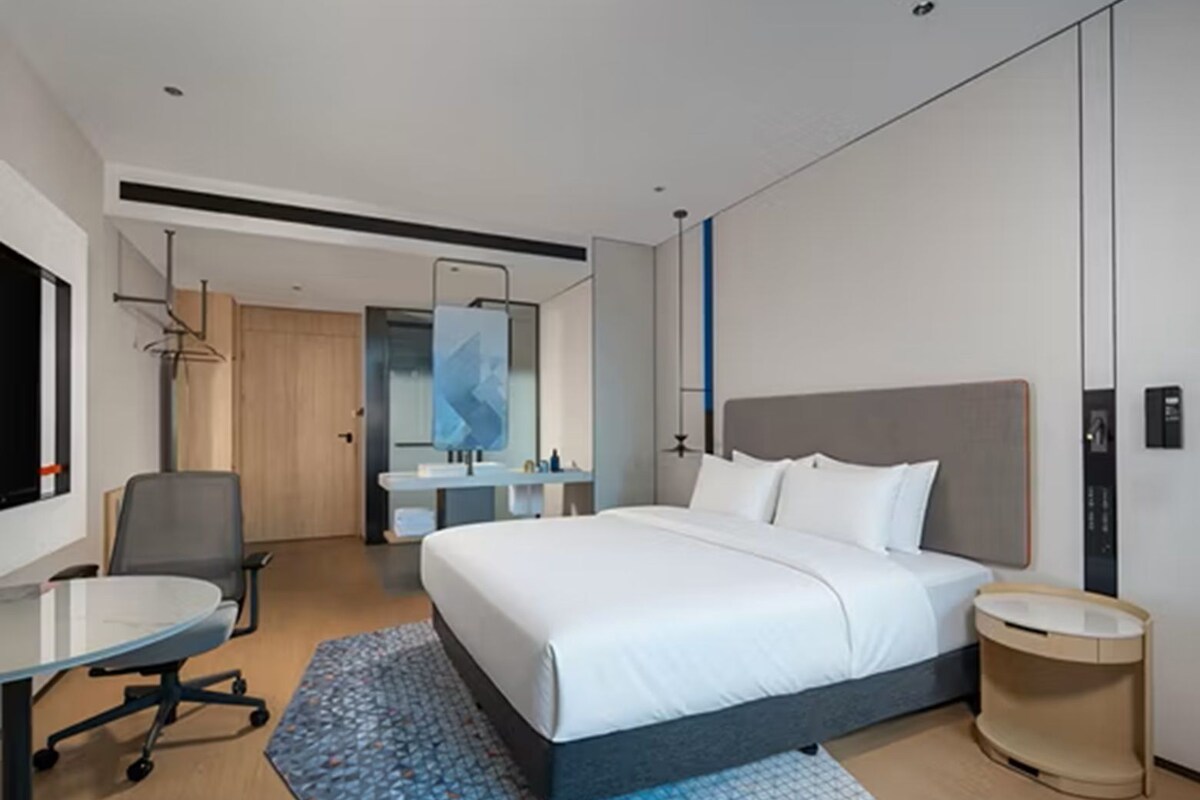 Una habitación de hotel moderna con una cama grande, un escritorio y un baño.